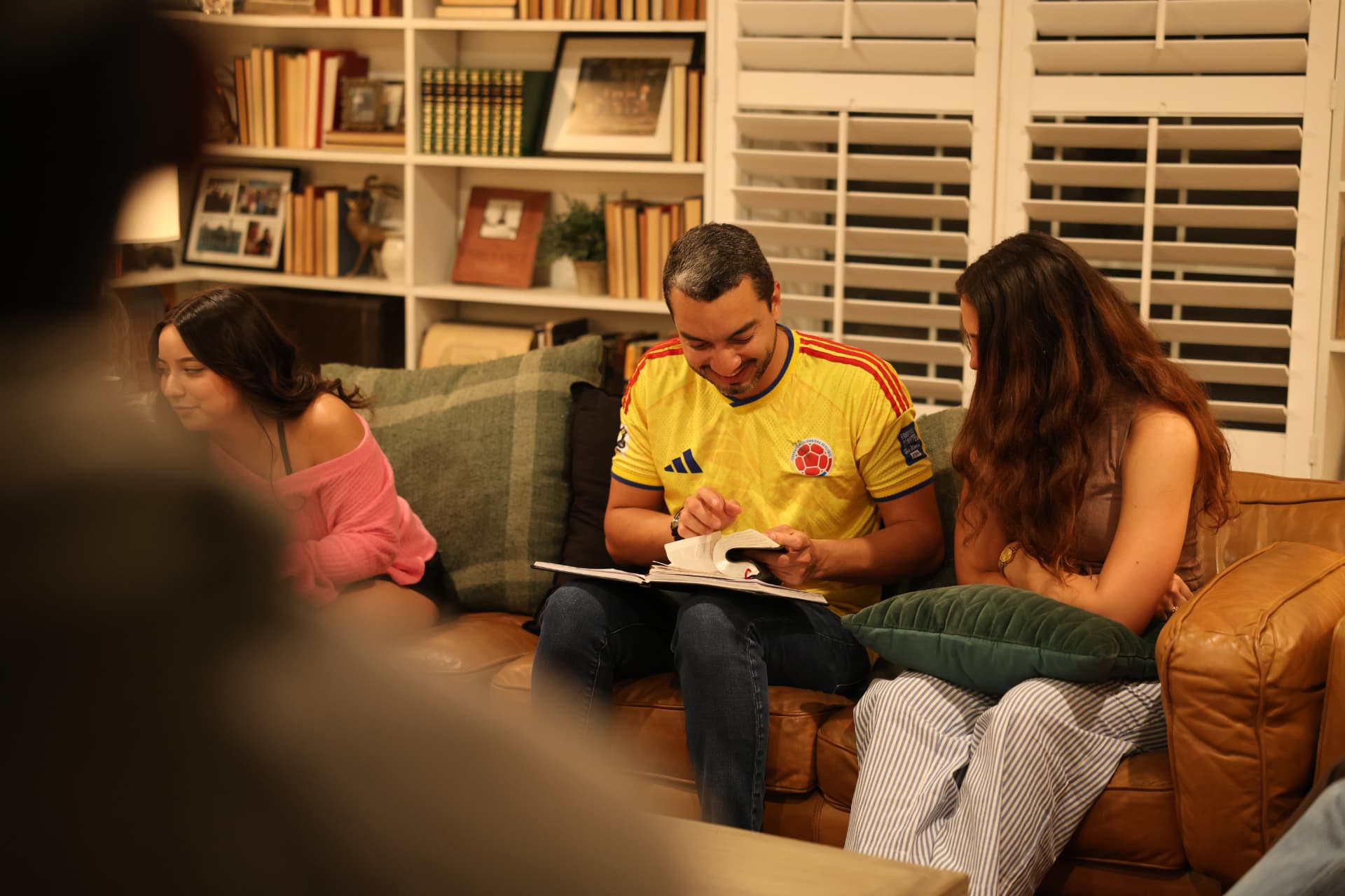A small group of friends gathered on a couch in a cozy living room, reading Scripture together