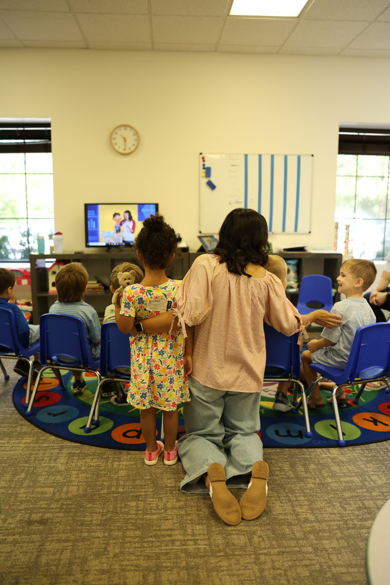 A Salt Kids leader kneeling beside children during a classroom lesson