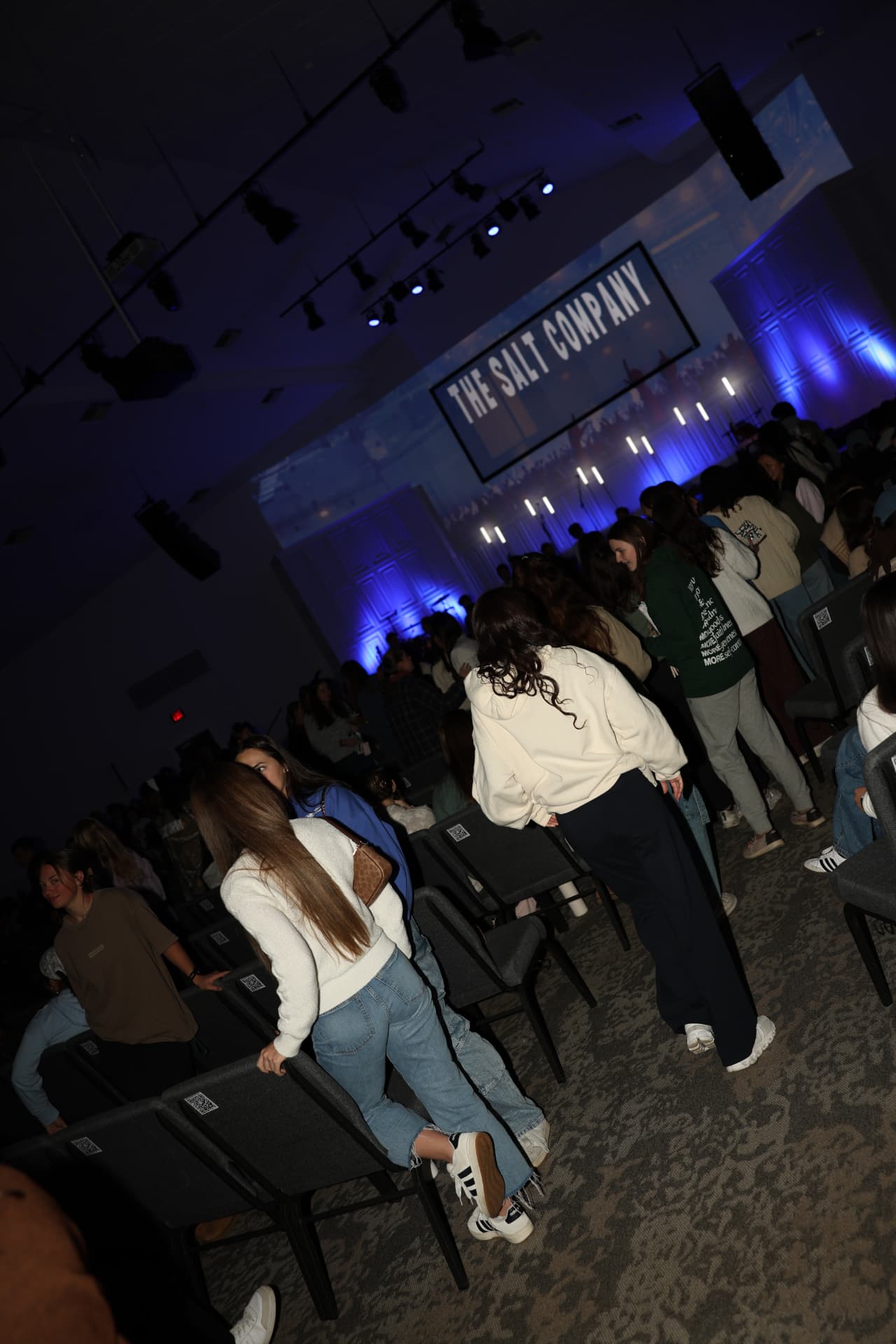 The room filling up under blue light with THE SALT COMPANY on screen