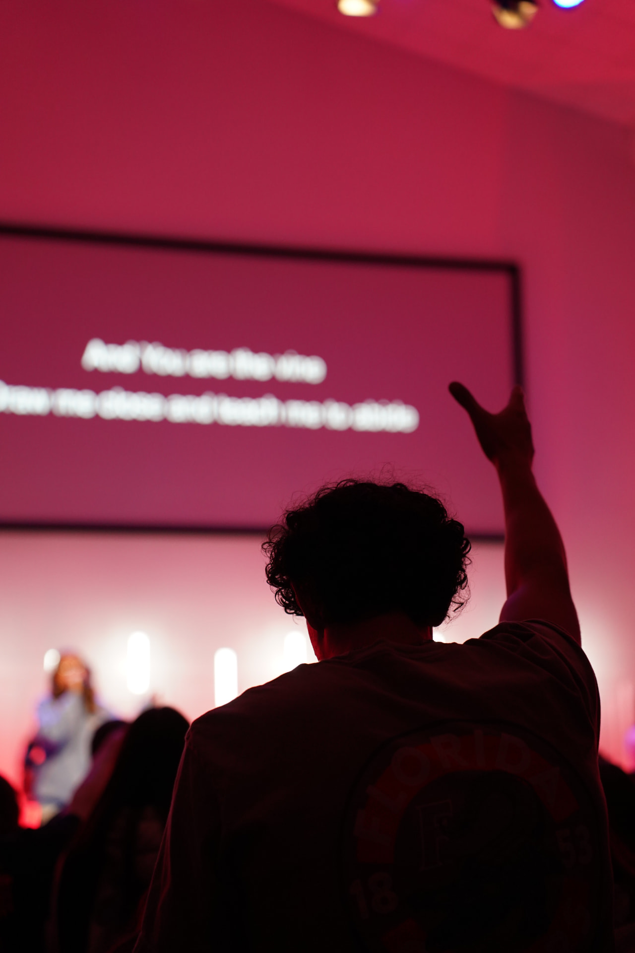 A student worshiping with a hand raised during a Thursday gathering